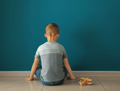 Chłopiec z autyzmem siedzi odwrócony twarzą do ściany