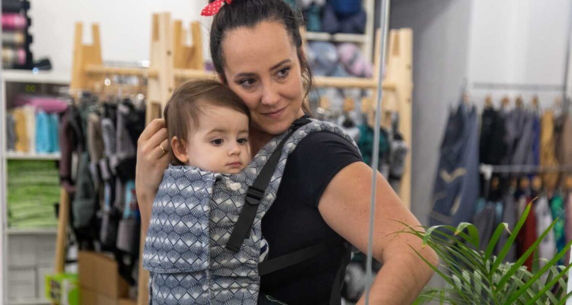 kobieta trzyma swoje dziecko w nosidełku